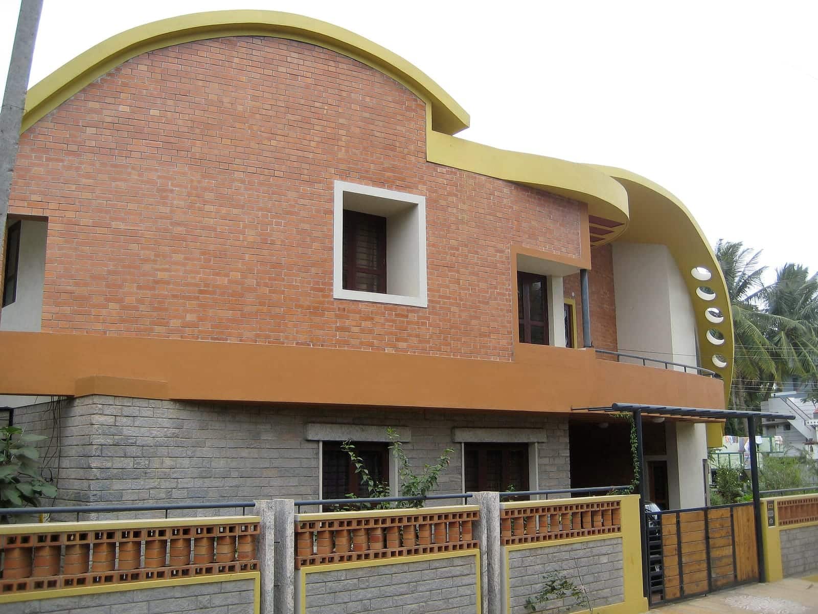 A modern two-storey house with exposed brick walls and a curved roofline