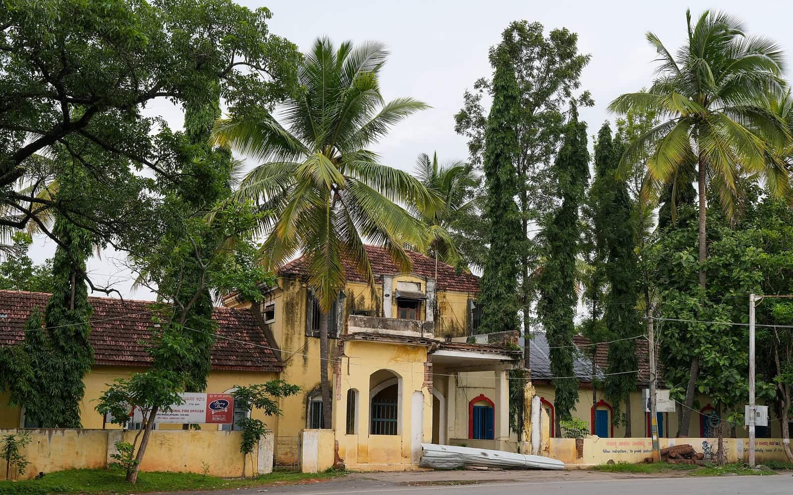 A heritage building in Mysuru framed by coconut palms