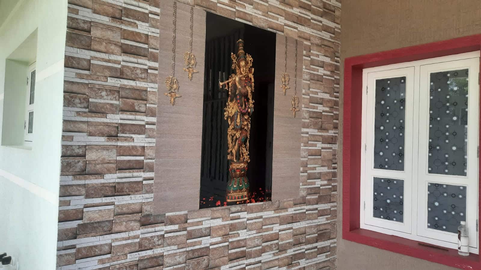 A stone-clad wall and a white-framed window in a Mysuru house