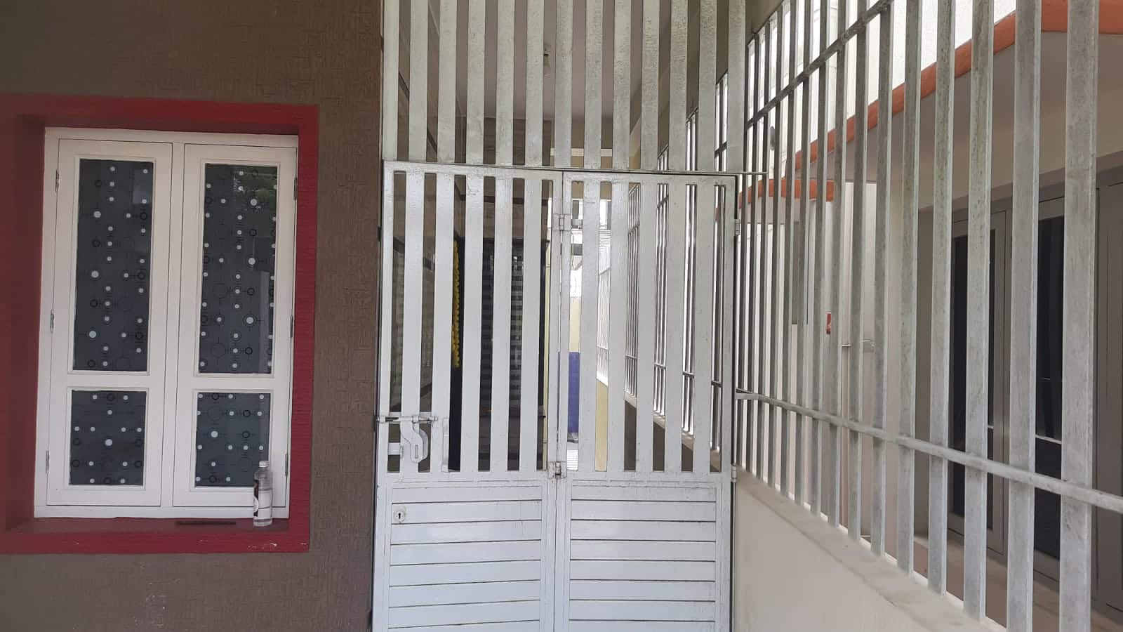 A window and white metal grille beside a staircase