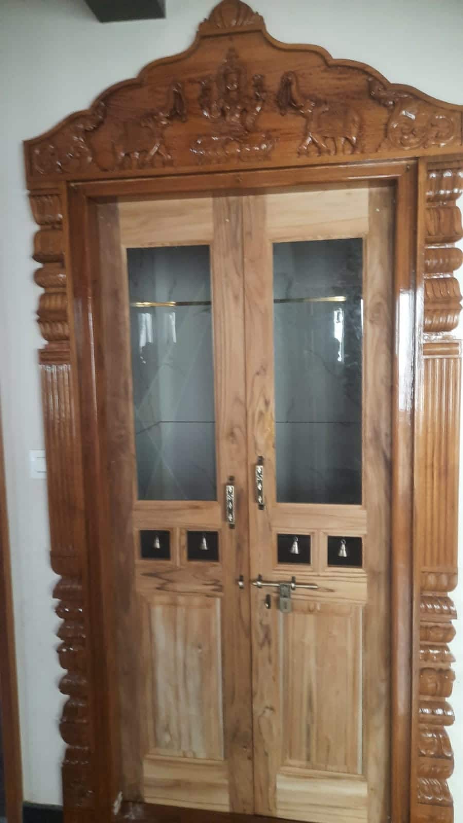 A carved teak front door with glass panels