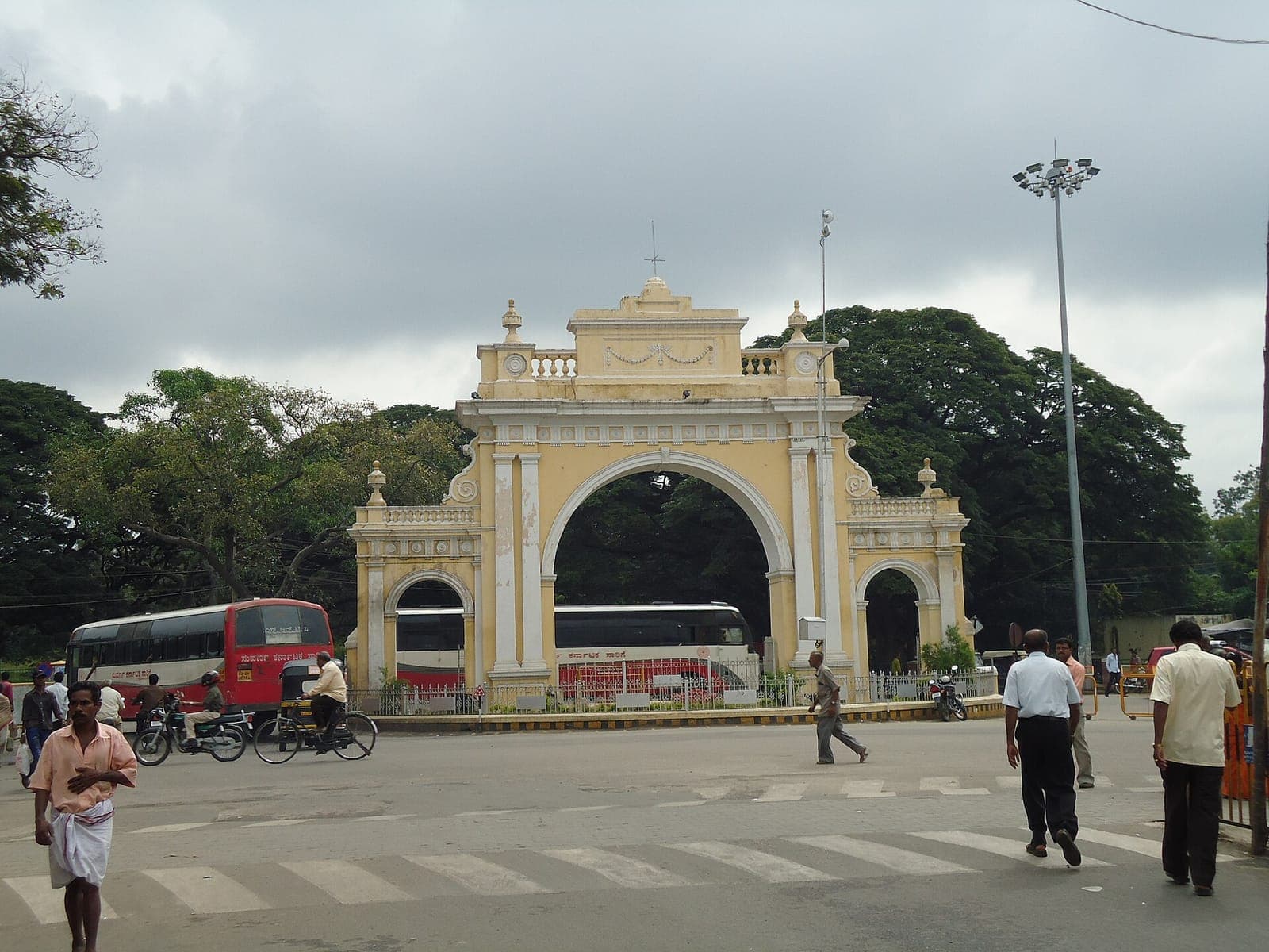 An arched gateway in Mysuru with city buses passing through