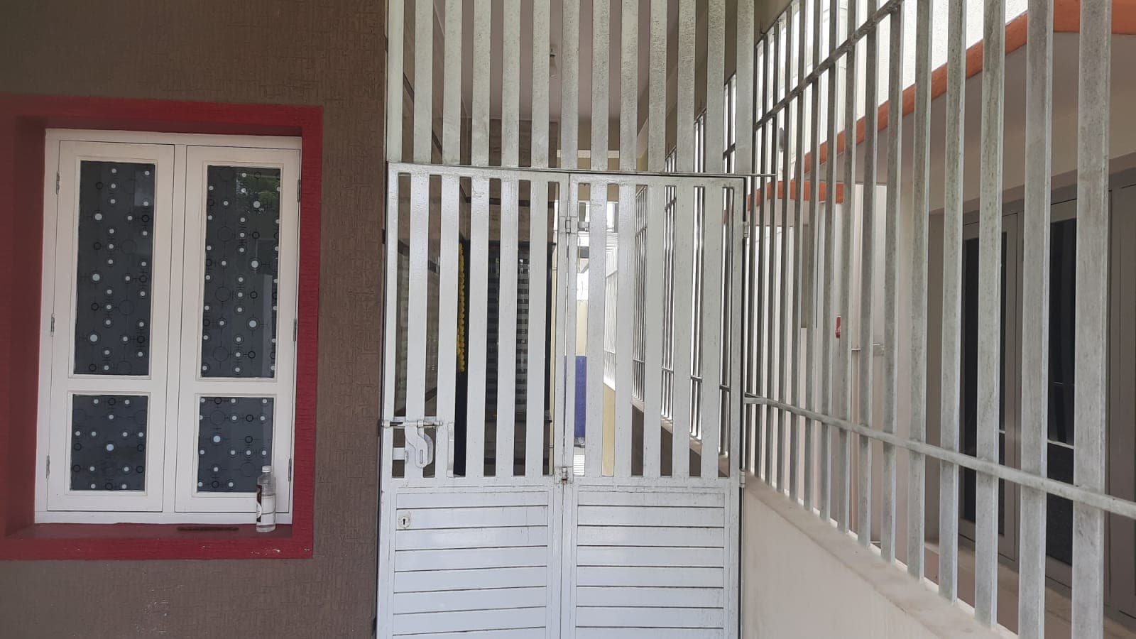 A window and white metal grille beside a staircase