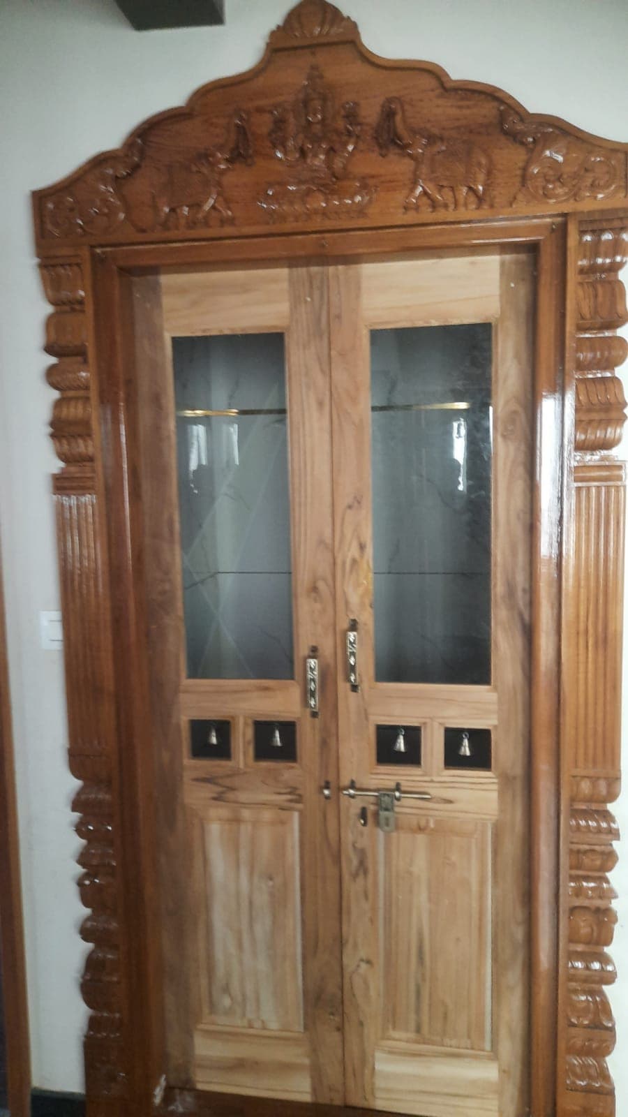 A carved teak front door with glass panels